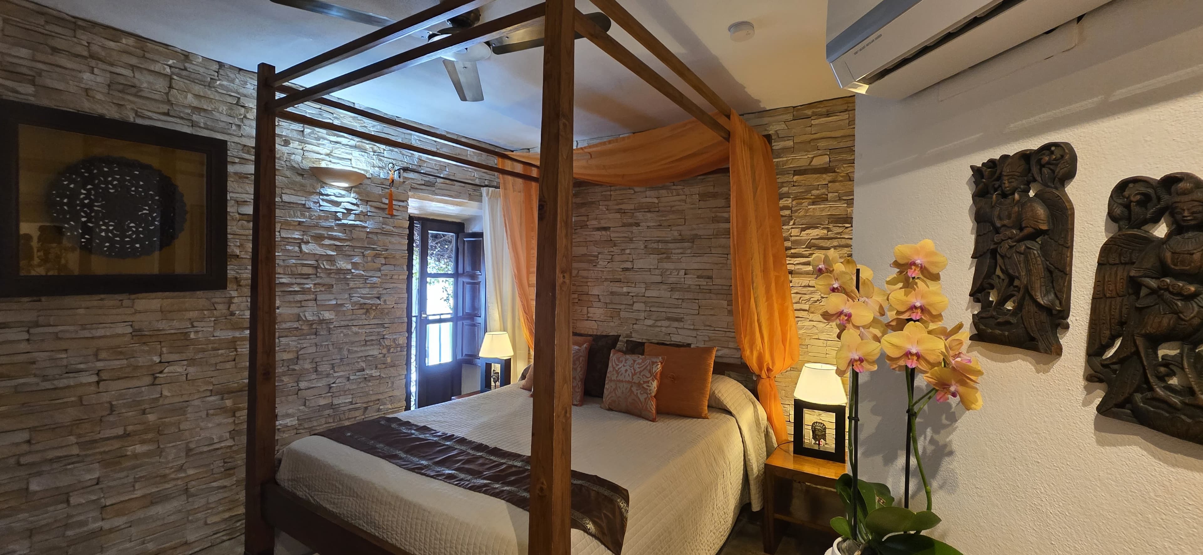 Four-poster bed framed by an Andalusian window in a guest room at La Villa Marbella